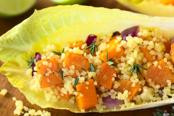 Endive leaves filled with a salad of couscous, pumpkin and red onion, sprinkled with fresh thyme leaves, photographed with natural light (Selective Focus, Focus in the middle of the image)