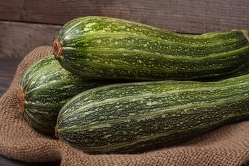 green zucchini on sackcloth and wooden background
