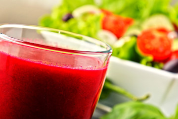 Composition with glass of juice and vegetable salad bowl.