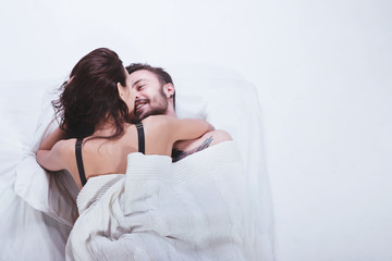 Beautiful loving couple is posing in a bed