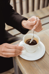 Hands with a spoon and a cup of black coffee