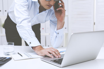 Standing businessman on the phone typing