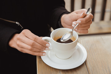 Hands with a spoon and a cup of black coffee