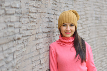 Portrait fashion cool girl in colorful clothes over wooden background wearing a  hat and pink  sweater