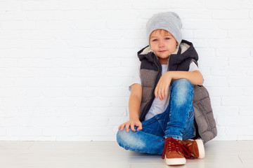 portrait of fashionable kid near the wall