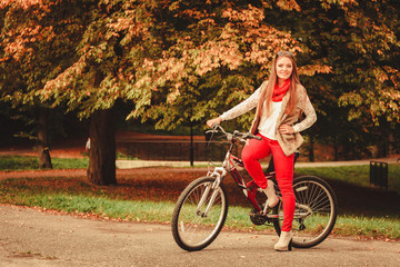 girl relaxing in autumnal park with bicycle.