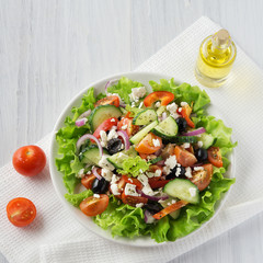 Fresh vegetable Greek salad with oil bottle, top view