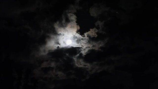 Noche de luna llena con fuerte resplandor de  la luna entre nubes y una estrella titilando
