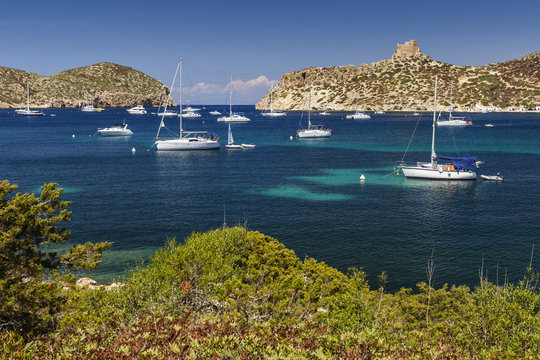 The island of Cabrera with boats anchored in the bay, dominated by the old castle. Balearic Islands, Spain.