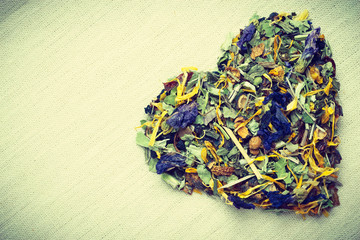 Dried herb leaves heart shaped on burlap surface