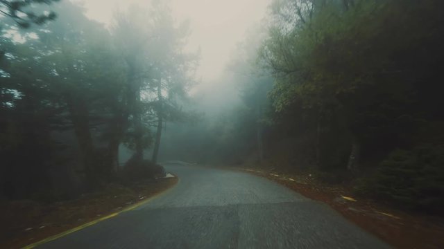 Pov driving on foggy dark scary mountain road at winter