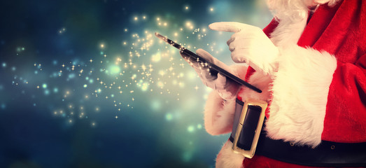 Santa Claus using tablet in snowy night