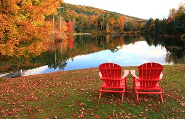 Fall in Vermont. Two red chairs overlooking a lake in Vermont.