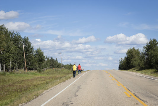 horizontal image of two women walking along side the highway to their truck in the summer time.