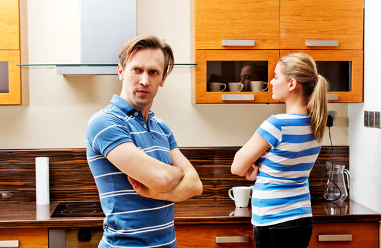 Quarreling couple standing in kitchen and don't talking with each other