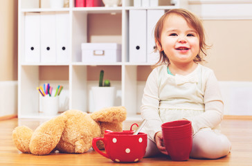 Toddler girl having tea time with her teddy bear