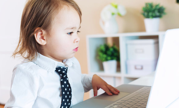 Serious toddler girl using laptop