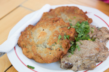 potato latkes served with mushroom thick sauce on white plate