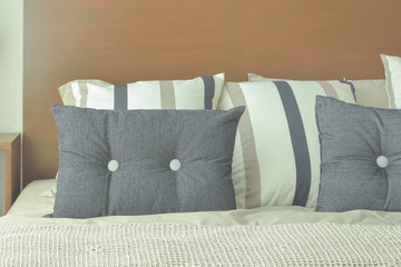 Gray and brown strip pillows setting on bed with brown headboard