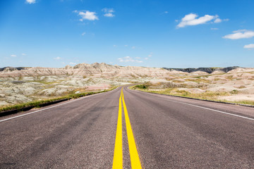 A road cutting through rolling hills in the Badlands of South Dakota on a summer day.