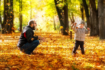 Happy father and son walking in autumn park