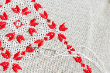 Embroidered fragment on flax by red and white cotton threads. Macro embroidery texture flat stitch.