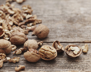 Walnut kernels and whole walnuts on rustic old wooden table