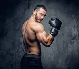 Aggressive shirtless boxer on grey background.