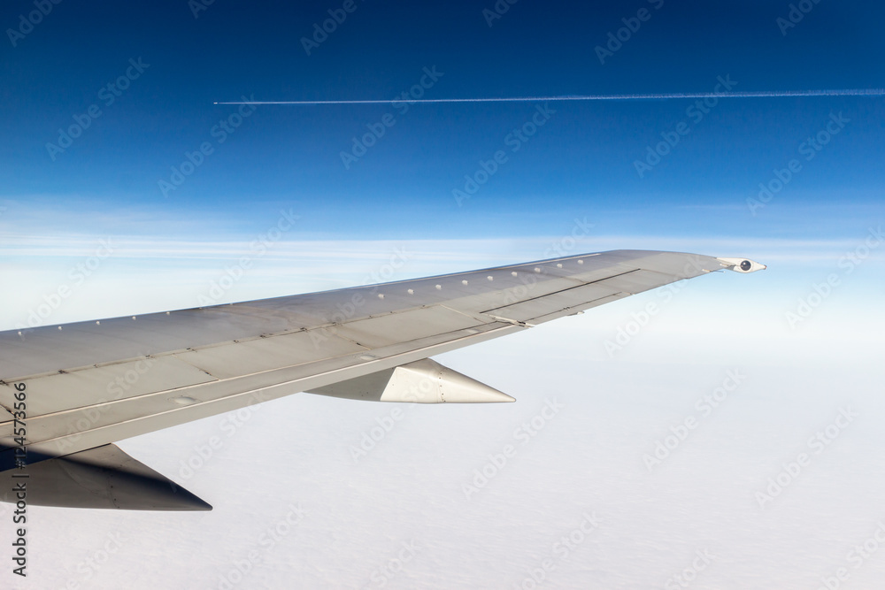 Canvas Prints wing of a plane on blue sky background. clouds underneath the wing. parallel plane in a distance wit