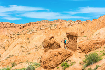 Fototapeta premium The beautiful girl in orange rocks of the canyon Tale, Kyrgyzsta