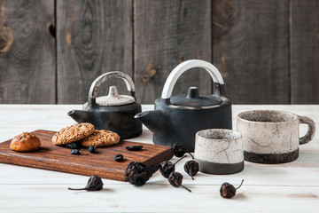 Old ceramic teapot with a Cup of tea and biscuits in a bowl on wooden background