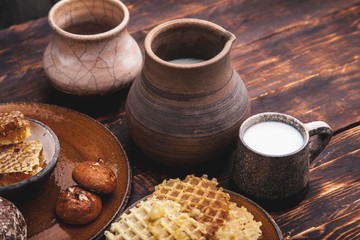Beautiful vintage ceramic jug with milk and honeycomb on brown wooden background