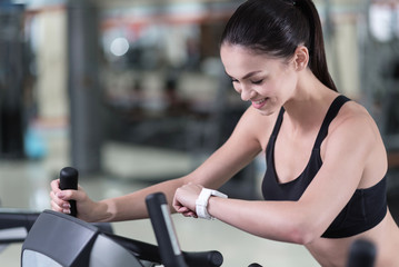 Fototapeta na wymiar Active woman looking at smart watch in a gym