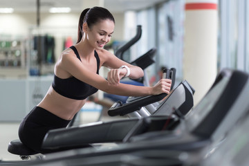 Fototapeta na wymiar Active girl running on a treadmill and wearing smart watch