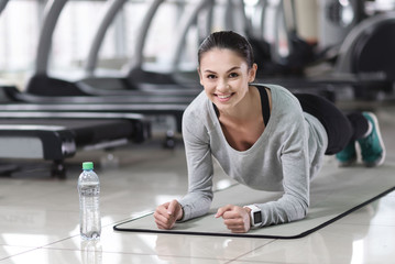 Smiling woman doing plank in a gym