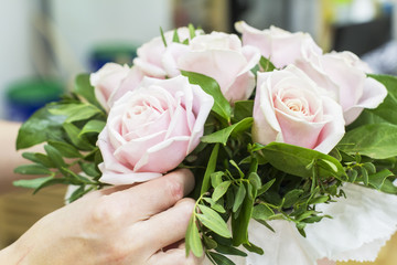 background florist girl collects bouquet of pink roses in a hatbox in the floristic salon