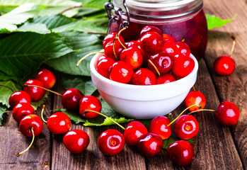 Fresh ripe cherries with jam on a wooden table.