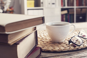 Pile of books with reading glasses on desk