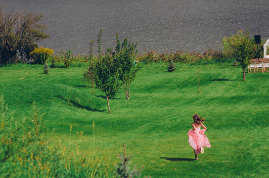 Girl running along a field at sunset