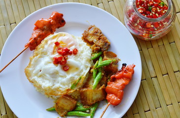 spicy stir fried crispy pork curry with egg and roasted pork stick