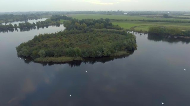 Approaching natural green island in the lake. Aerial view