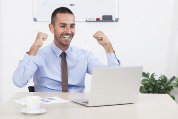 Happy businessman working in his office on the laptop