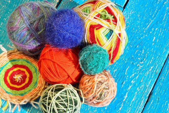 Piles of multi-colored colorful balls from wool on blue wooden background. Background for needlework