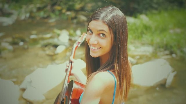 beautiful woman playing guitar at the river
