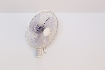 electric fan hanging on white wall