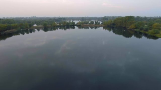 Natural lakes in misty morning. Fastfoward flyby. Fen Drayton, Cambridgeshire, UK. Aerial shot
