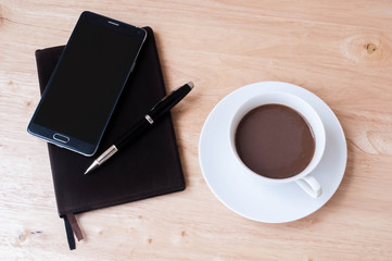 notebook phone and coffee cup on wooden table