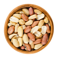 Shelled peanuts in wooden bowl on white background. Dry roasted Arachis hypogaea, also called groundnut and goober, used as a snack. Isolated macro food photo close up from above.
