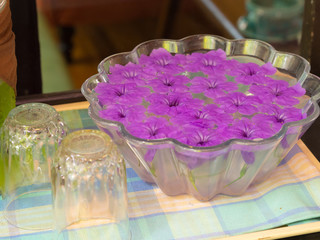 Obraz na płótnie Canvas Purple flowers floating on glass jar. on a wooden table.