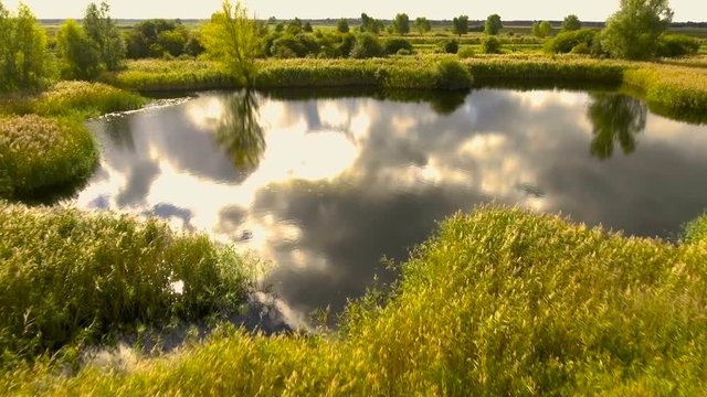 Natural pond reflecting sun and sky of water surface. Aerial view